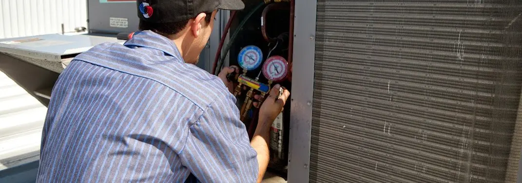 HVAC technician servicing a condenser unit in Grand Haven