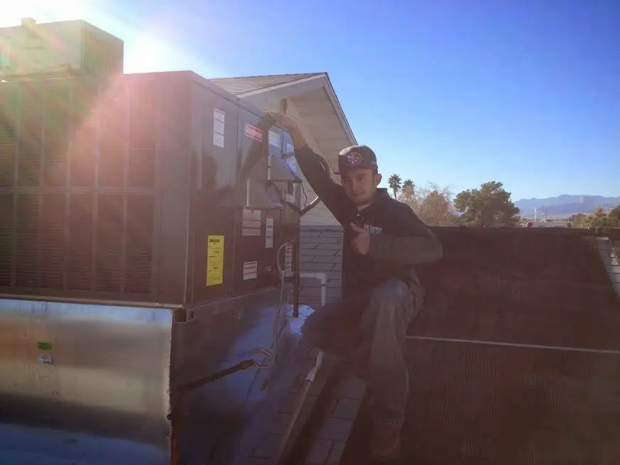 HVAC technician performing AC Tune-Up on a rooftop unit in Grand Haven